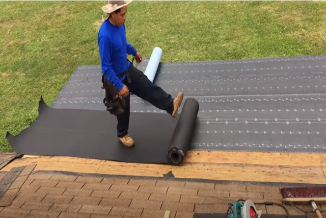 Worker adding insulation pad for commercial flat roof