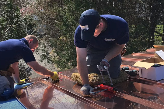 Worker installing copper metal roofing